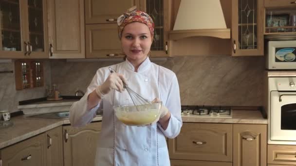 En kvinne på kjøkkenet forteller resepsjonen, blander ingredienser med visp i en glassbolle. En dame på kjøkkenet skriver en oppskrift på bloggen sin. – stockvideo