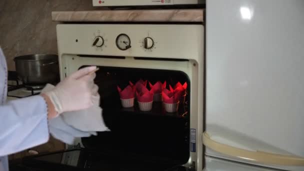 Vrouw gebak chef-kok in de keuken haalt bakplaat uit een hete oven en vertrouwt de bereidheid van gebak met een houten stokje — Stockvideo