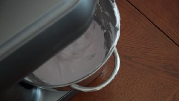 Процесс создания сладкого десерта планетарным миксером на белом креме с пищевым красителем в стальной чаше и получением нежного густого розового крема — стоковое видео