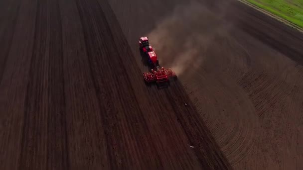 Panorama del paisaje agrícola, un tractor moderno, un arado con rastrillos que se mueven en dirección recta arada el suelo para la siembra de cultivos, vista aérea — Vídeo de stock