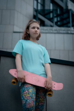 Güzel genç kız güneşli bir günde sokakta elinde bozuk para tahtasıyla dikiliyor.