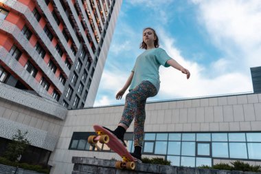 Güzel genç kız güneşli bir günde sokakta elinde bozuk para tahtasıyla dikiliyor.