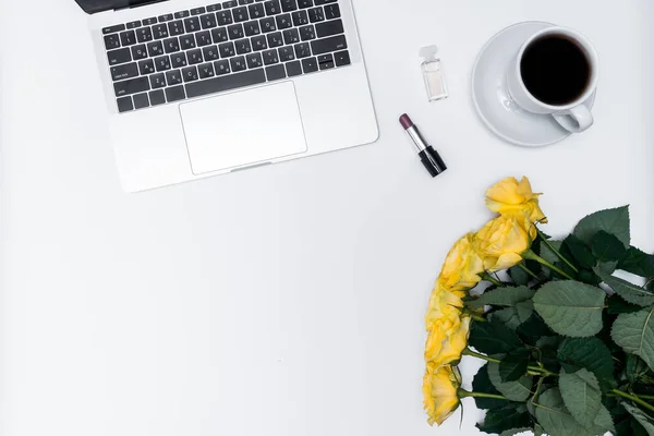 Kadın işyeri, sarı güller, dizüstü bilgisayar ve kupa beyaz arka planda