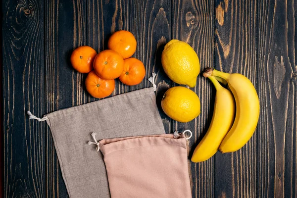 Tahta masada, geri dönüşümlü eko poşetlerde taze meyveler.