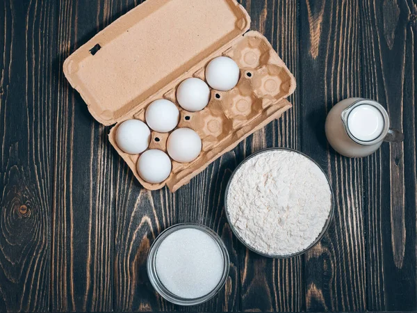 Pasta malzemeleri: un, şeker, ahşap masa üzerinde yumurta, düz yatak