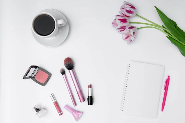 Kadın kozmetik ürünleri, kahve ve beyaz arka planda boş defter