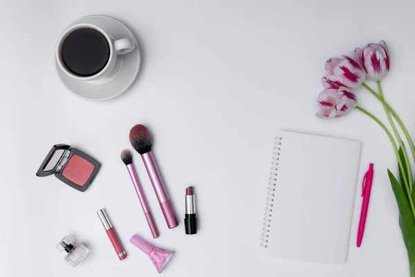 Kadın kozmetik ürünleri, kahve ve beyaz arka planda boş defter