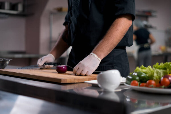 Man gloved hands cooking fresh healthy greek salad at restaurant kitchen