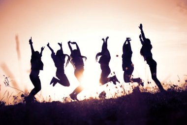 Gökyüzüne karşı kutlama yapan gençlerin silueti. .