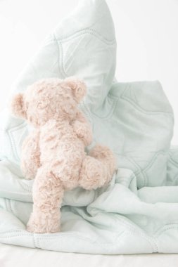 Oyuncak ayı battaniye yığınına tırmanıyor, yaramaz bebek.