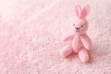 Yumuşak kumaşın üzerinde sevimli pembe bir tavşan oturuyor. 