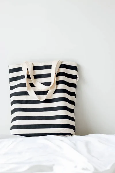 striped shopper bag on bed by white wall