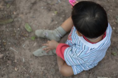 Küçük bir çocuk yerde oturuyordu.