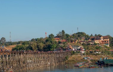 Mavi gökyüzü altındaki insanlarla köprü ve liman manzarası