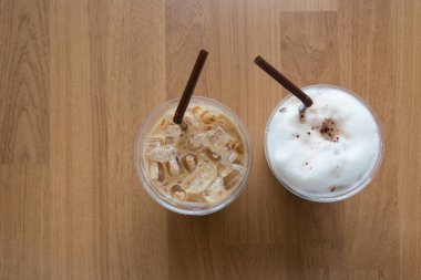 Ahşap arka planda plastik pipetli buzlu kahve.