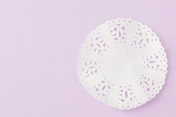 Белая круглая салфетка на фиолетовом фоне