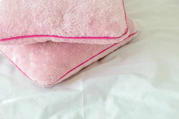 Pembe yumuşak yastıklar beyaz yatak çarşafları üzerinde
