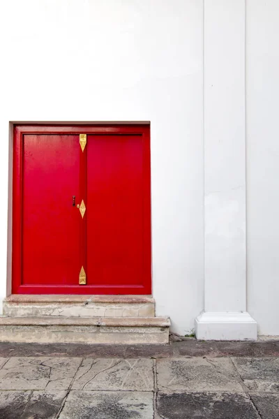 red door with stairs on white building