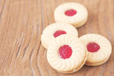 Ahşap arka planda ahududu reçelli kurabiyeler