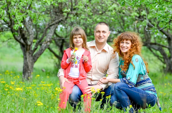 Maman, papa et fille marchant dans le jardin vert — Photo