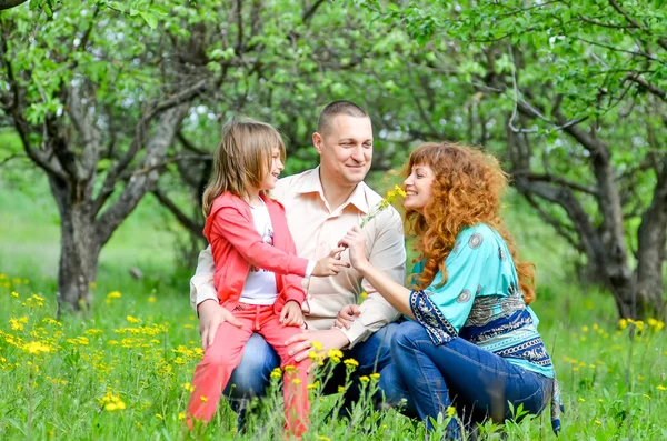 Mamá, papá e hija caminando en el jardín verde — Foto de Stock