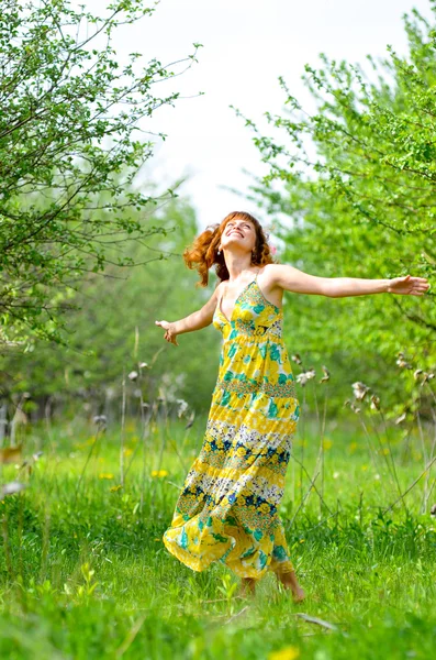 Молодая красивая девушка ходит в весенний зеленый яблоневый сад — стоковое фото