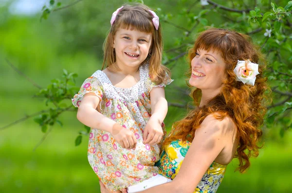 Jovem bela mãe andando com sua filha no jardim — Fotografia de Stock