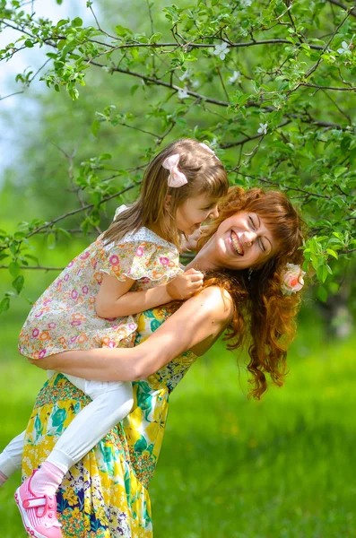 Jovem bela mãe andando com sua filha no jardim — Fotografia de Stock