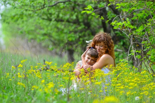 Junge schöne Mutter spaziert mit ihrer Tochter im Garten — Stockfoto