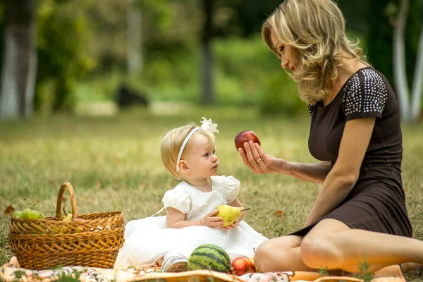 Mother walks with the child in the garden in summer.