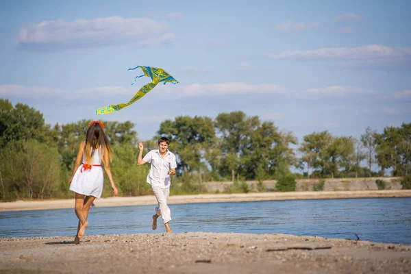 Girl with a guy run kite flying on the beach in spring, summer. — Stock Photo, Image