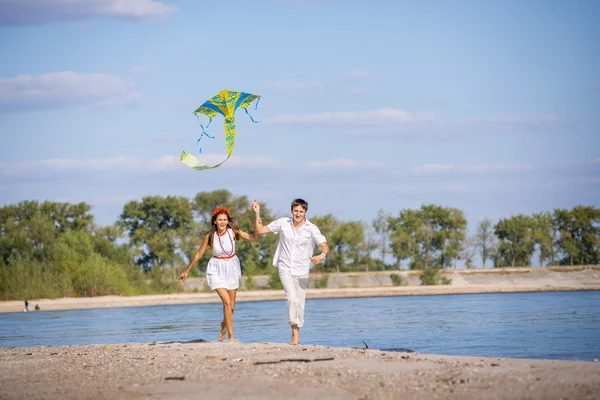 Girl with a guy run kite flying on the beach in spring, summer. — Stock Photo, Image