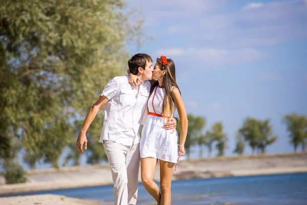 Chica feliz con el chico sentado en la playa en primavera, verano . — Foto de Stock