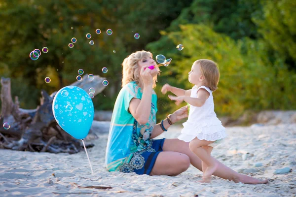 Mama met een dochter spelen op het strand — Stockfoto