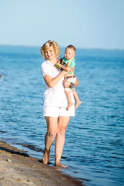 Moeder met peuter wandelen op het strand. — Stockfoto