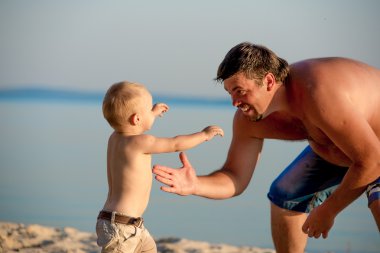 Baba oğlu ile kumsalda oynarken.