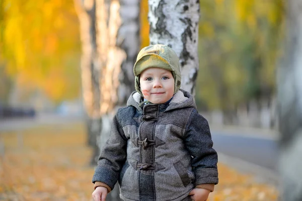 小男孩站在秋天里附近的树上 — 图库照片