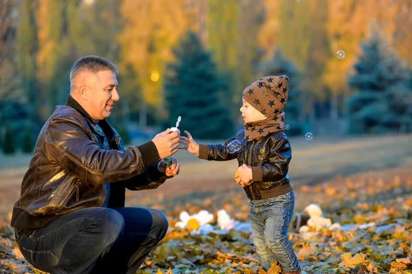 Vader spelen met zijn zoon in het park in het najaar. — Stockfoto
