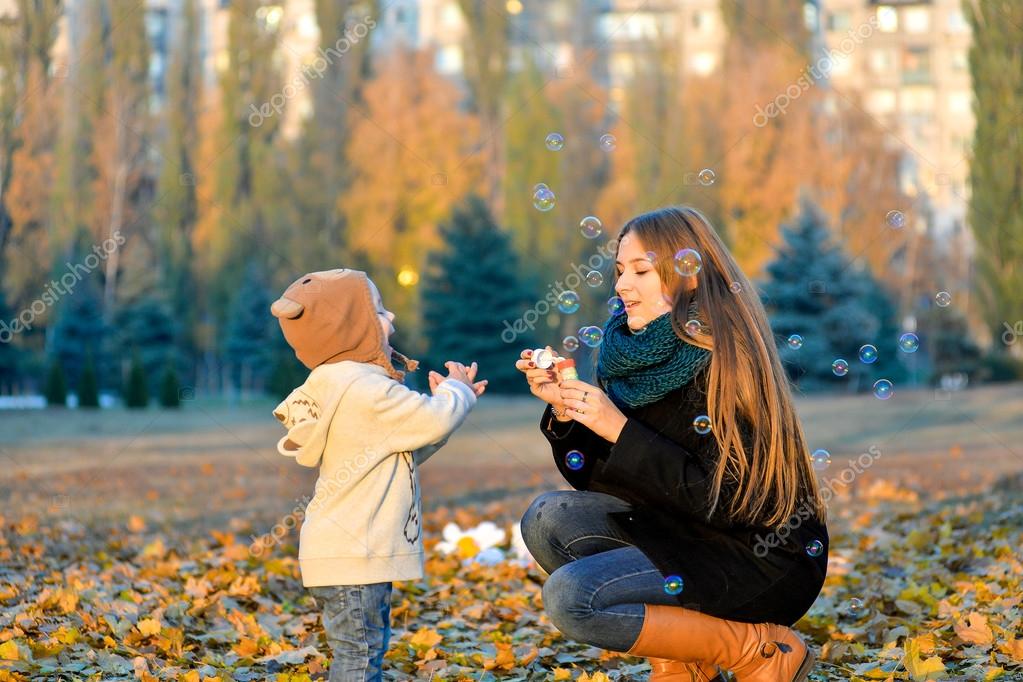 Little Boy Playing With His Sister In The Park In Autumn Girl Blowing Soap Bubbles And Little Brother Catches Them Cheerful Happy Kids Playing In The Little Boy Playing With His Sister In The Park In Autumn Girl Blowing Soap Bubbles And Little Brother Catches Them Cheerful Happy Kids Playing In The