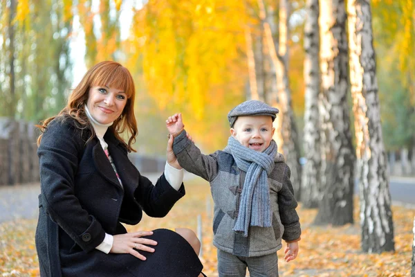 Moeder met baby in het park in het najaar. — Stockfoto