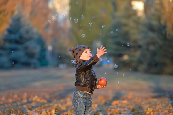 Apple ile sonbaharda bir parkta duran yürümeye başlayan çocuk — Stok fotoğraf