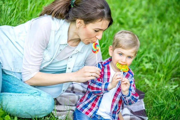 Moeder met baby in het park eten snoep. — Stockfoto