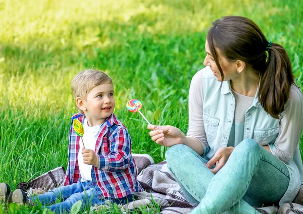 Moeder met baby in het park eten snoep. — Stockfoto