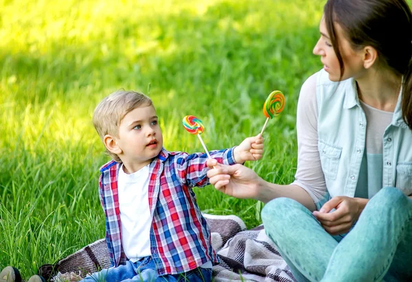 Moeder met baby in het park eten snoep. — Stockfoto