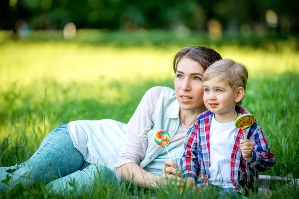 Moeder met baby in het park eten snoep. — Stockfoto