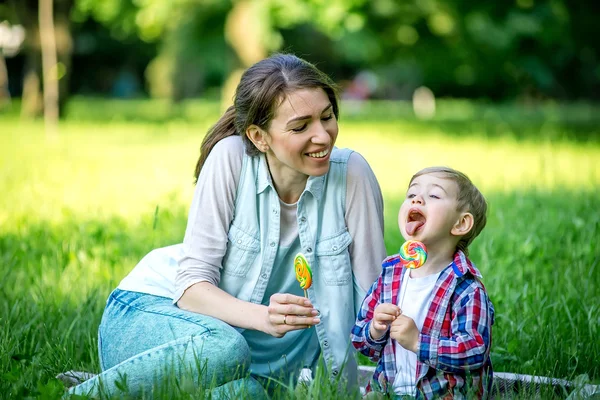 Moeder met baby in het park eten snoep. — Stockfoto