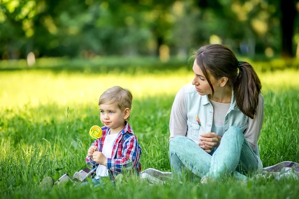 Mãe com bebê no parque comer doces . Fotografias De Stock Royalty-Free