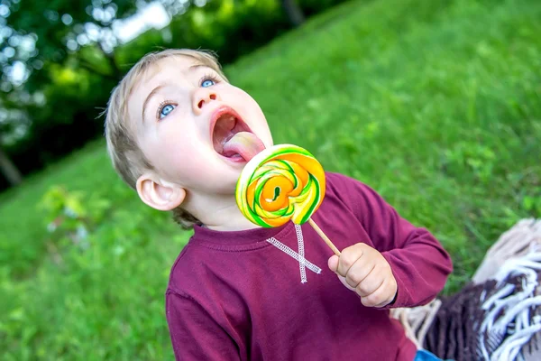 Μικρό παιδί που τρώει ένα γλειφιτζούρι στο πάρκο — Φωτογραφία Αρχείου