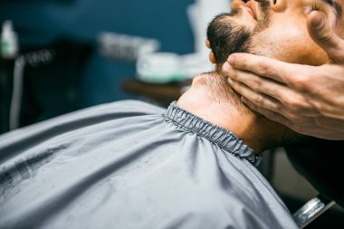 Kuaför sakallı adam keser.