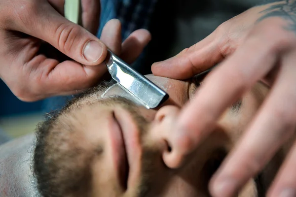 The barber cuts the beard man.